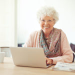 Cheerful Senior Woman at Home with Laptop